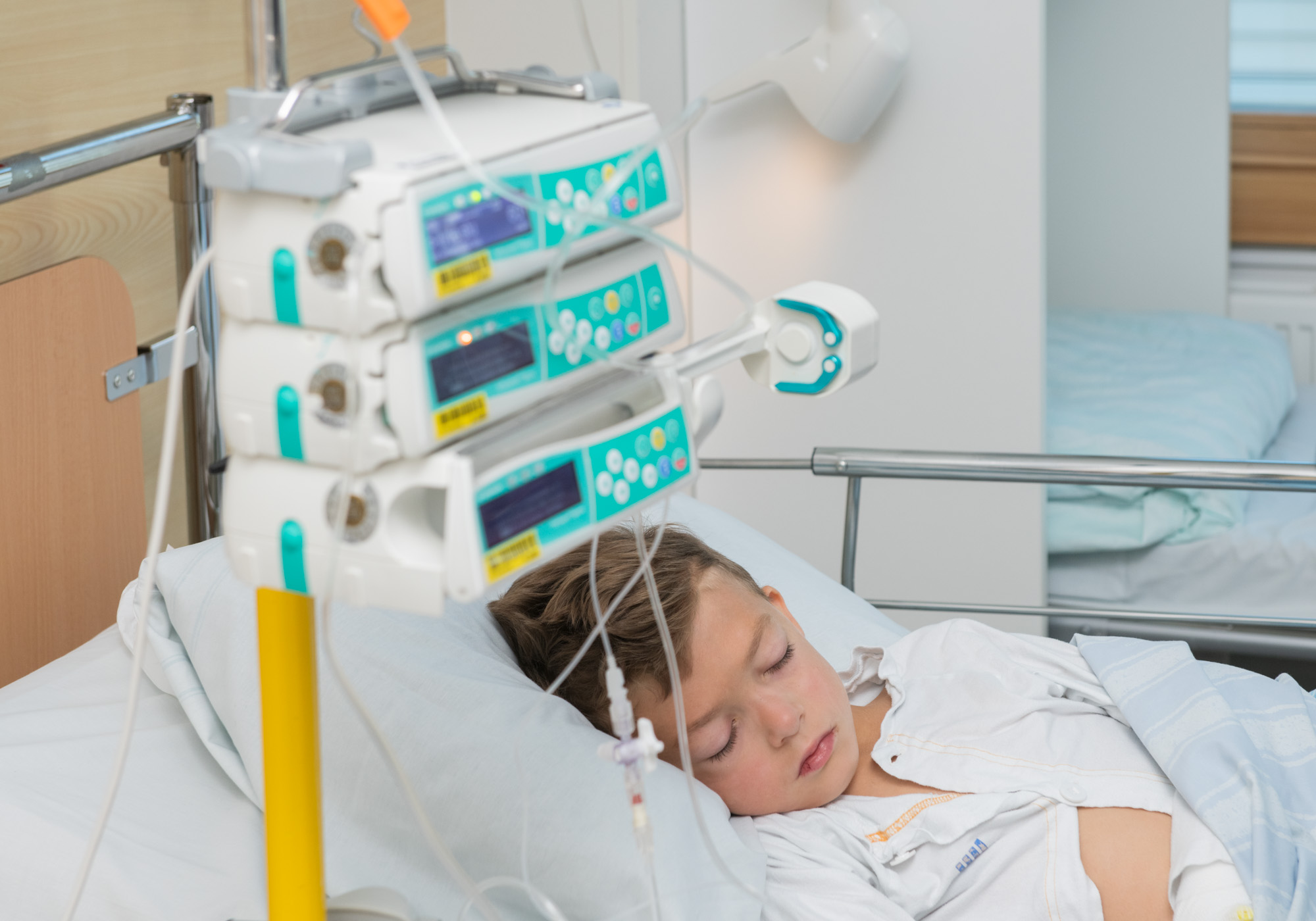 Pojke i säng med infusionspumpar bredvid.