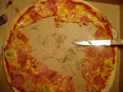 En halväten pizza och en kniv i en pizzakartong