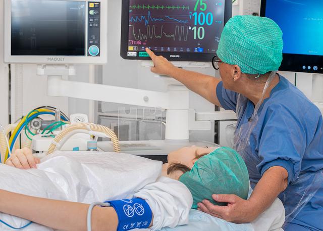 Patient ligger på ett operationsbord och tittar på övervakningsskärmen tillsammans med en sjuksköterska.